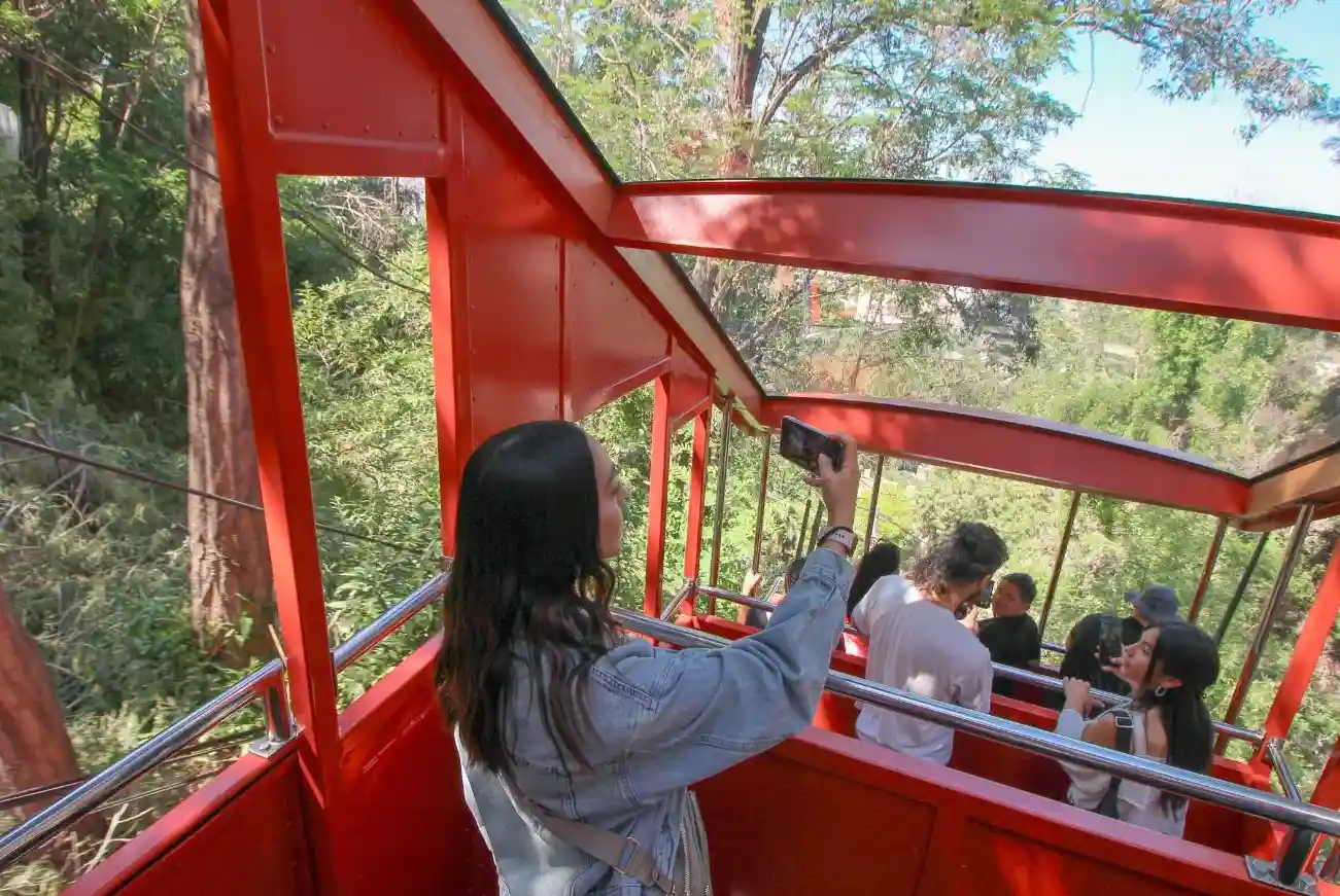 Pasajeros fotografiando el paisaje desde el interior del carro abierto del Funicular Santiago
