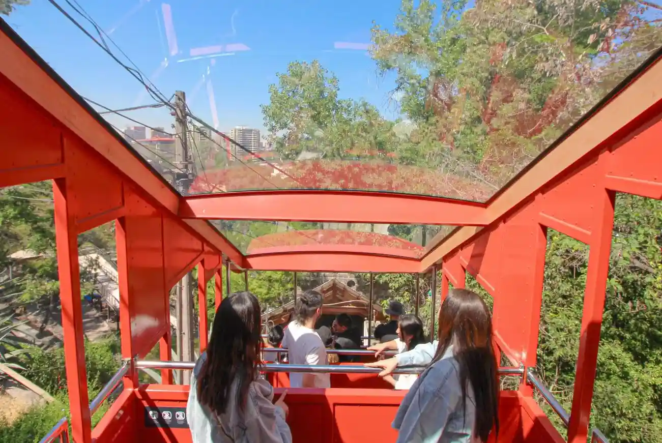 Pasajeros a bordo del carro panorámico del Funicular Santiago rodeados de vegetación nativa